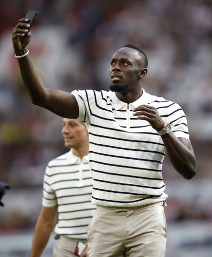 Usain Bolt en train de se prendre en photo durant un match de charité organisé par l'UNICEF à Old Trafford